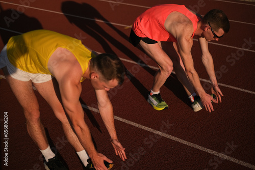 Two runners do warm-up bending exercises at the stadium before the race