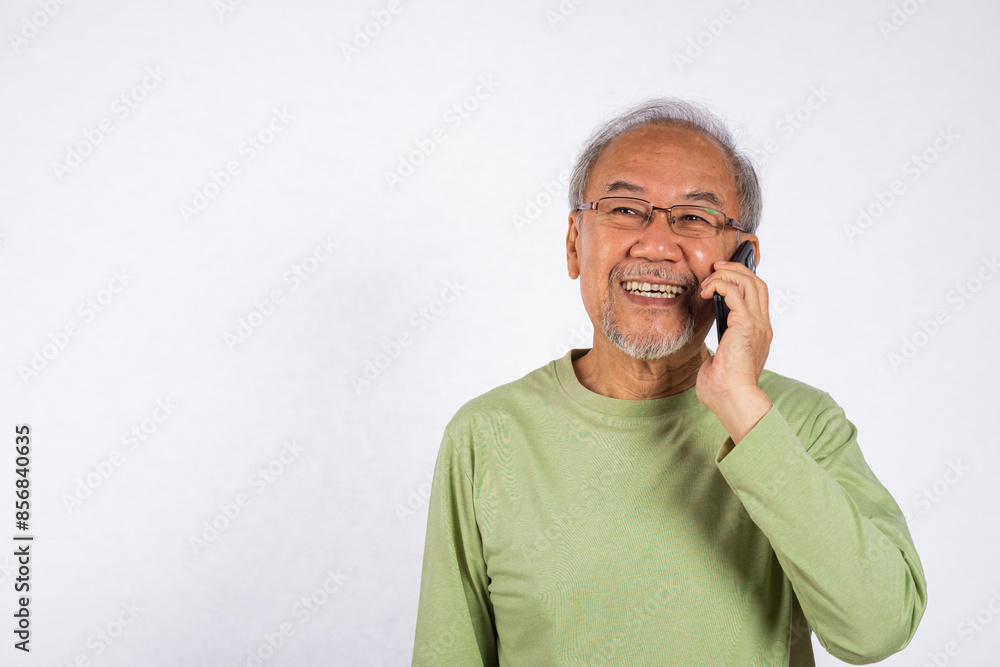 Portrait Asian smiling old man with glasses while talking on his cell phone studio shot isolated on white background, happy senior man calling to someone with mobile phone Portrait Asian smiling old man with glasses while talking on his cell phone studio shot isolated on white background, happy senior man calling to someone with mobile phone