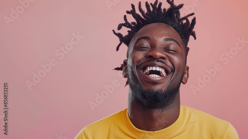 Man with dreadlocks laughs against a pink wall