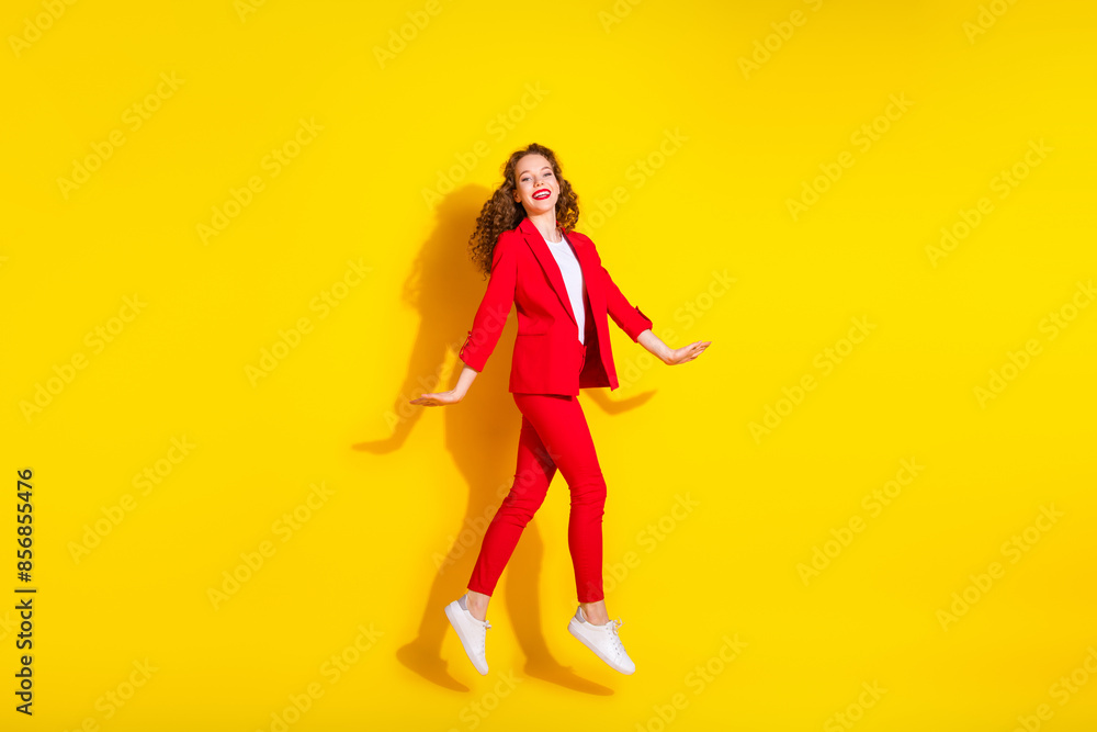 Full body portrait of gorgeous young lady jump empty space wear red suit isolated on yellow color background Full body portrait of gorgeous young lady jump empty space wear red suit isolated on yellow color background