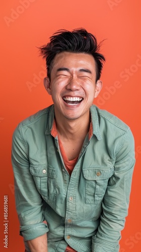 A man laughs joyfully in front of an orange background © Sasa Visual