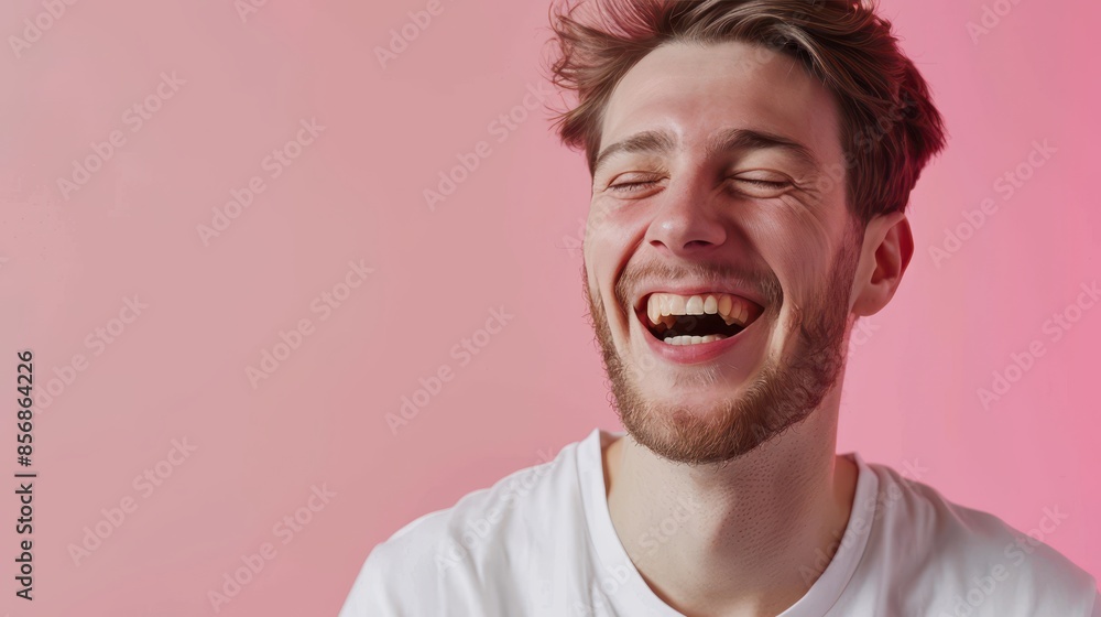 A man laughs with eyes closed against a pink backdrop A man laughs with eyes closed against a pink backdrop