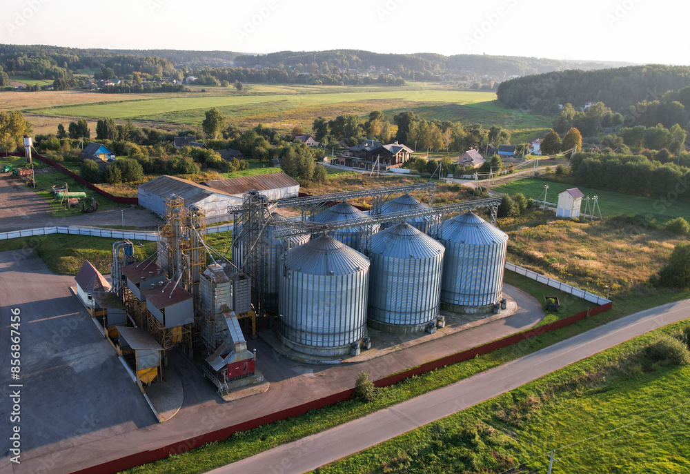 Grain storage Silo at farm, drone view. Wheat flour mill. Elevator for corn storage and grain. Feed Silos Hopper for wheat storage, barley. Wheat flour plant. Grain drying in Steel Silo, aerial view. Grain storage Silo at farm, drone view. Wheat flour mill. Elevator for corn storage and grain. Feed Silos Hopper for wheat storage, barley. Wheat flour plant. Grain drying in Steel Silo, aerial view.