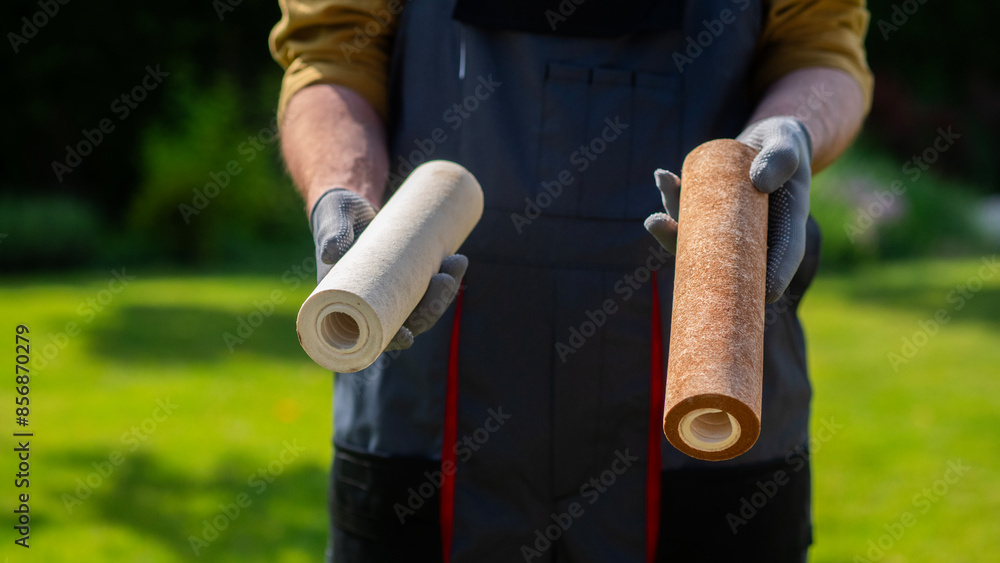 Plumber in gloves showing two dirty drinking water filters. Plumber in gloves showing two dirty drinking water filters.