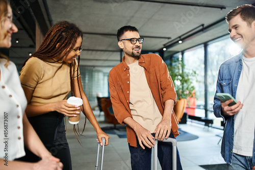 Fototapeta Multicultural colleagues in casual attire standing in a circle, interacting and conversing in a hotel lobby during a corporate trip