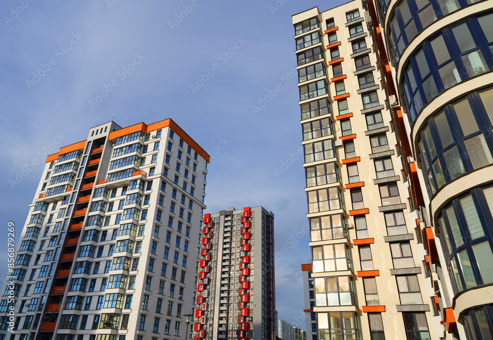 Naklejka premium Facade building. Modern building and houses against blue sky. Colorful buildings with glass windows, balconies. Buildings architecture. Skyline Skyscrapers. Urban Residential building exterior.