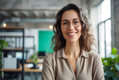 Close-up of a smiling mid adult businesswoman Close-up portrait of smiling mid adult businesswoman standing in office. Woman entrepreneur looking at camera and smiling photo