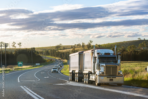 Truck driving on rural road in country followed by cars of mine shift workers heading home