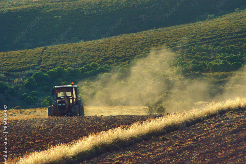 Fototapeta premium Tractor Working the Soil in a Field on a Sunny Day