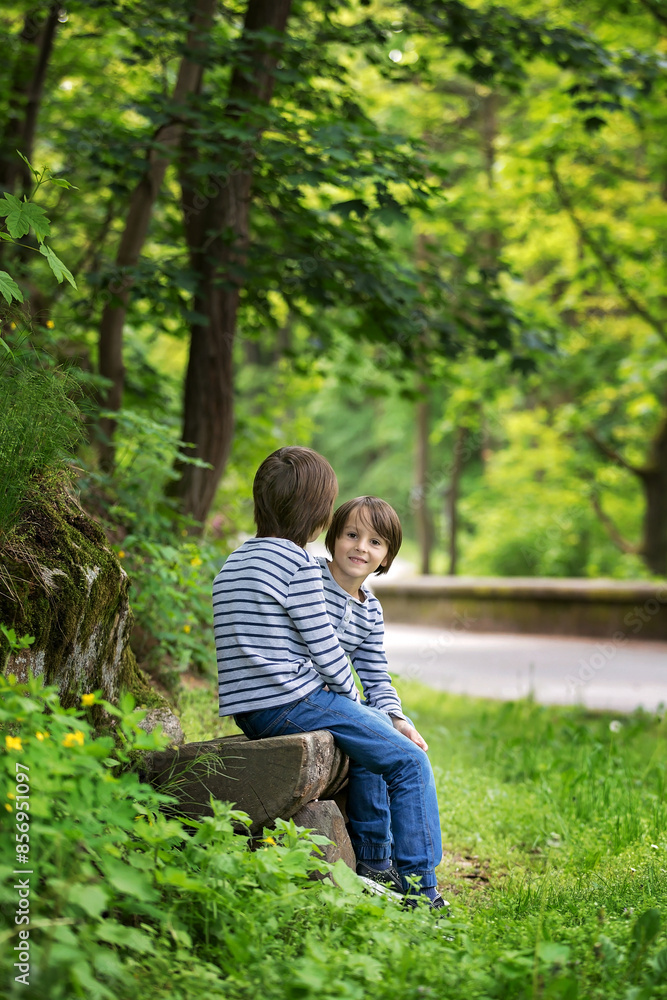Sweet twin brothers, children sitting on bench in park Sweet twin brothers, children sitting on bench in park