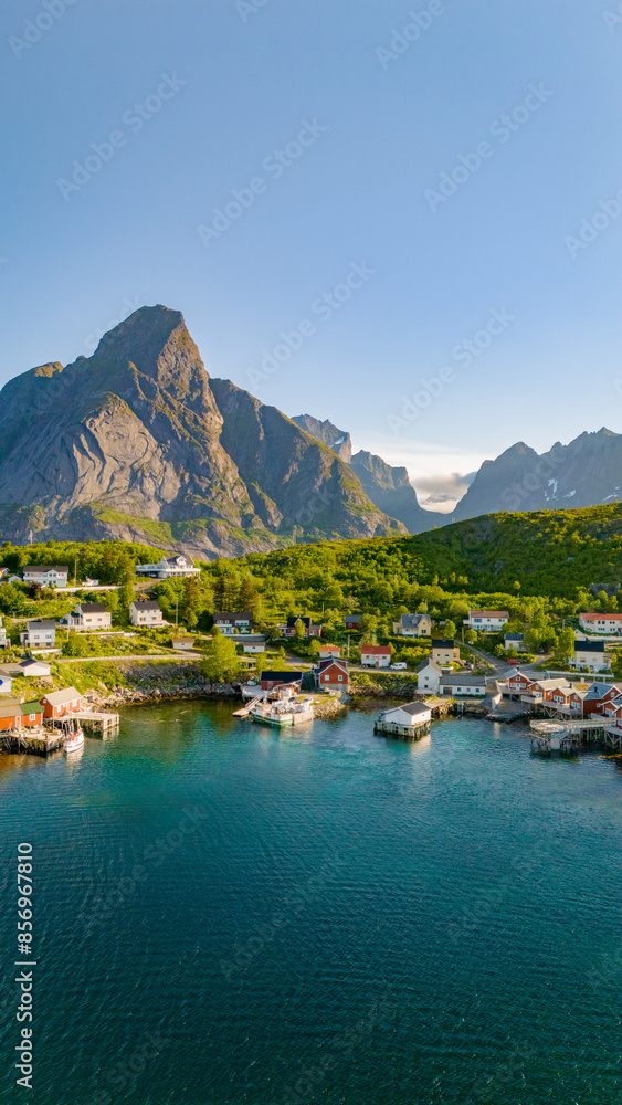 Fototapeta premium An aerial view of a peaceful harbor in Lofoten, Norway, surrounded by majestic mountains and lush green hills. Reine, Lofoten, Norway