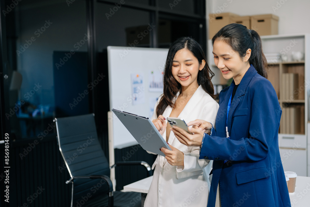 Two business workers talking on the smartphone and using laptop at the office.. Two business workers talking on the smartphone and using laptop at the office..