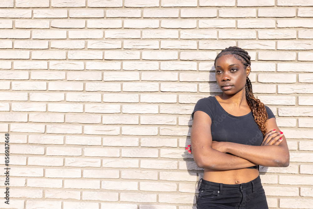 A confident young woman stylishly poses against a brick wall, exuding urban, modern attitude in this candid portrait A confident young woman stylishly poses against a brick wall, exuding urban, modern attitude in this candid portrait