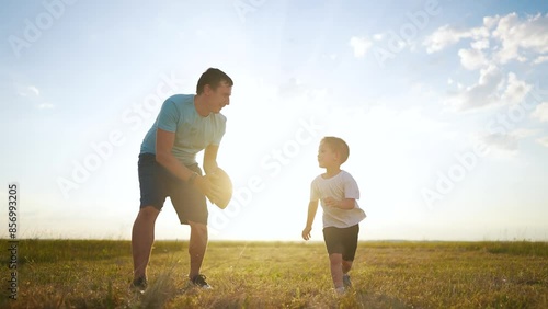A father teaches his son to play football. Soccer child parent family concept. Father and son playing football with ball. Father teaches his son to play fun football. family happy childhood concept.