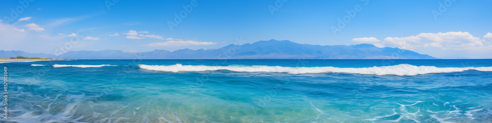 The ocean is calm and blue, with a few waves breaking on the shore The ocean is calm and blue, with a few waves breaking on the shore