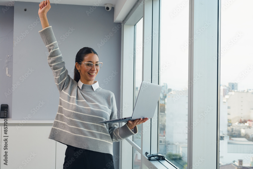 Woman in the office celebrating the profits of her digital investments Woman in the office celebrating the profits of her digital investments