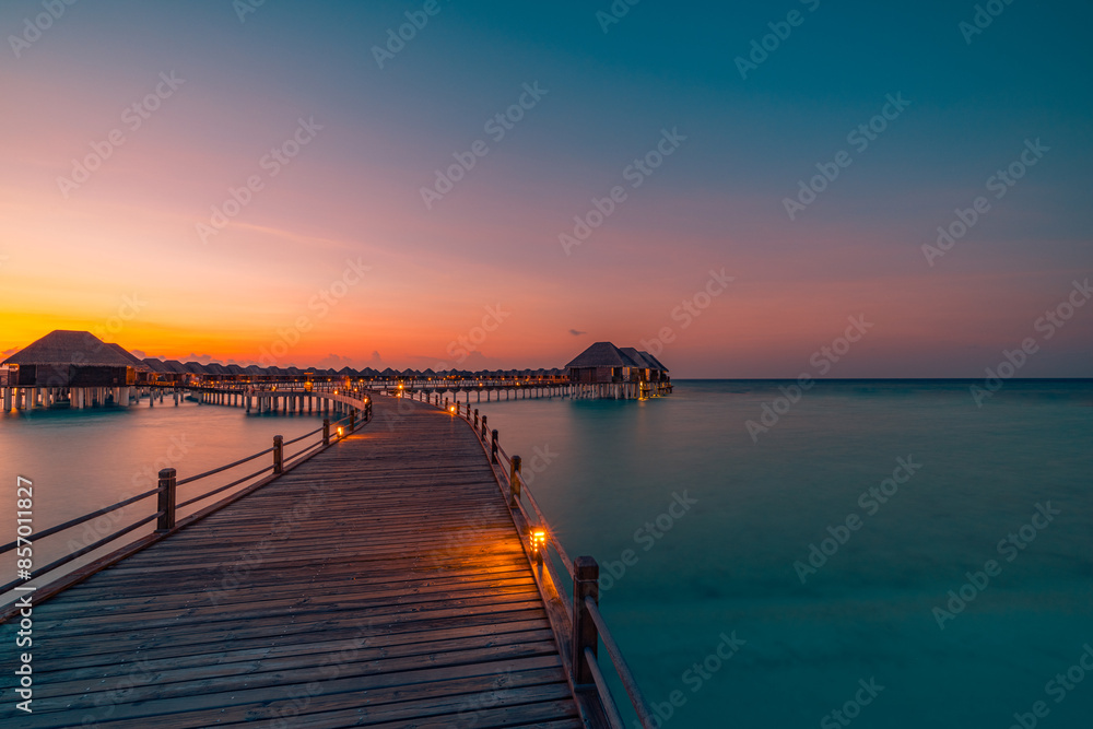 Obraz premium Amazing beach landscape. Beautiful Maldives sunset seascape view. Horizon colorful sea sky clouds, over water villa pier pathway. Tranquil island lagoon, tourism travel background. Exotic vacation