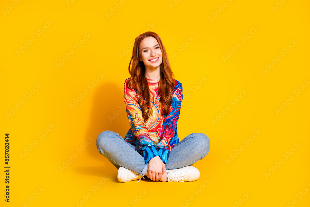 Full length photo of lovely young lady sit floor crossed legs dressed stylish colorful garment isolated on orange color background Full length photo of lovely young lady sit floor crossed legs dressed stylish colorful garment isolated on orange color background