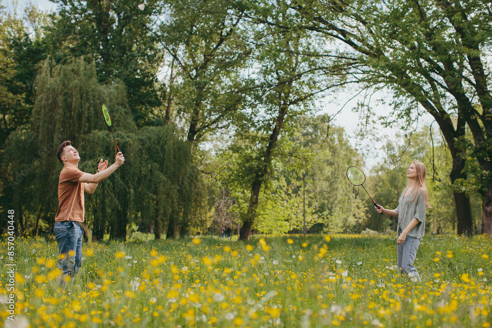 Happy Caucasian couple playing badminton with rackets and shuttlecock in city park. The concept of active recreation. Happy Caucasian couple playing badminton with rackets and shuttlecock in city park. The concept of active recreation.