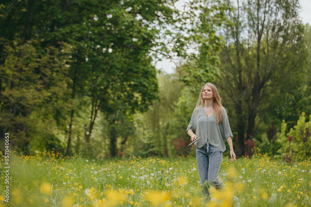 A young blonde woman plays badminton on a lawn in a park. A young blonde woman plays badminton on a lawn in a park.