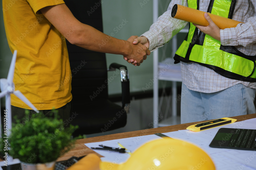 construction worker wearing a protective helmet and vest is holding his colleague's hand while working at the job site. construction worker wearing a protective helmet and vest is holding his colleague's hand while working at the job site.
