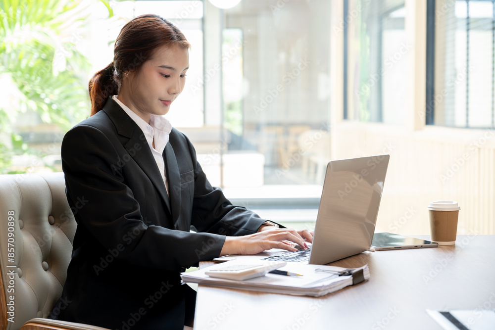 A beautiful young Asian businesswoman or female secretary working on her laptop computer in a office. businesspeople, technology A beautiful young Asian businesswoman or female secretary working on her laptop computer in a office. businesspeople, technology
