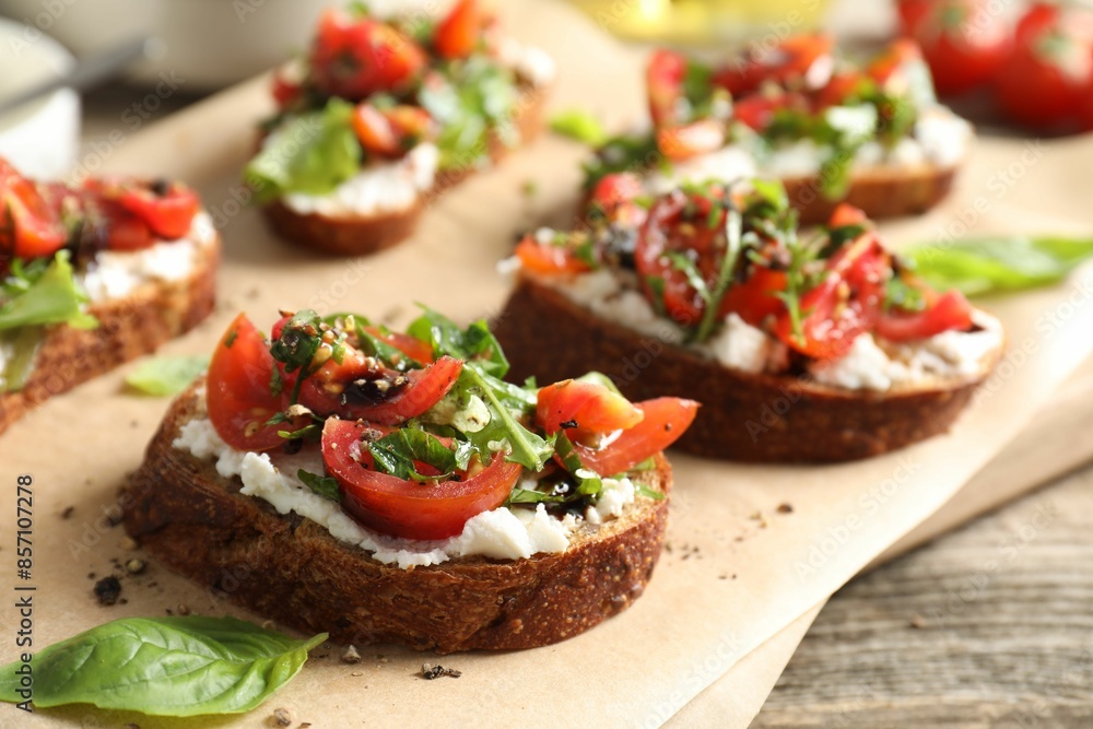 Delicious ricotta bruschettas with tomatoes, arugula and basil on wooden table, closeup Delicious ricotta bruschettas with tomatoes, arugula and basil on wooden table, closeup