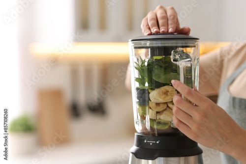 Canvastavla Woman making delicious smoothie with blender in kitchen, closeup