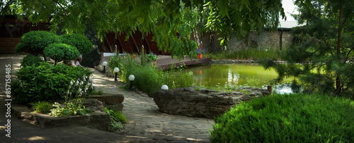 a cozy corner of the garden, a pond and various bushes and trees, landscape d...