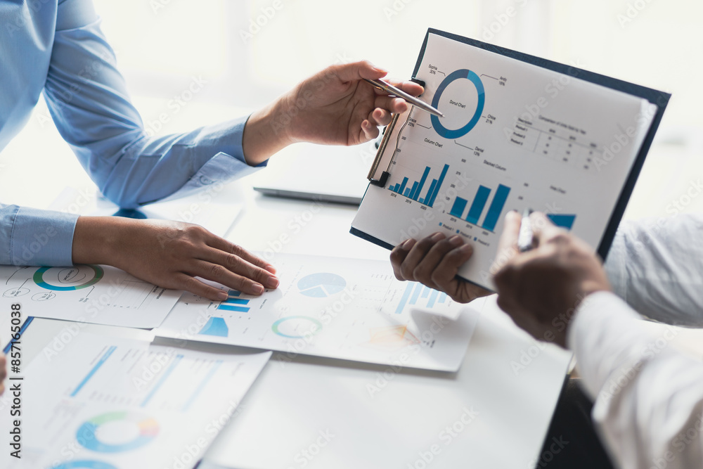 Business consulting meeting is discussing business plan analysis with financial data and business growth charts to plan strategies for generating company profits. Business consulting meeting is discussing business plan analysis with financial data and business growth charts to plan strategies for generating company profits.