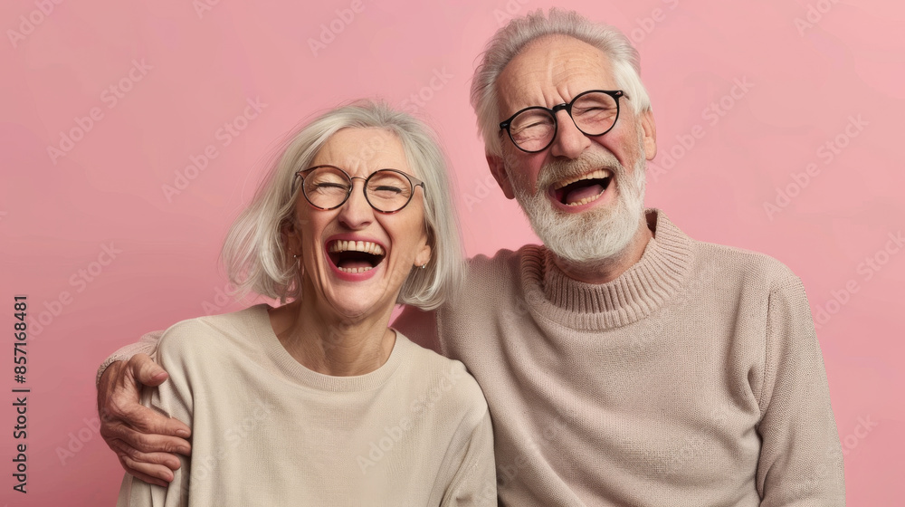 An elderly couple with matching white hair and glasses share a jubilant laugh against a pastel pink background, exuding pure joy and contentment. An elderly couple with matching white hair and glasses share a jubilant laugh against a pastel pink background, exuding pure joy and contentment.