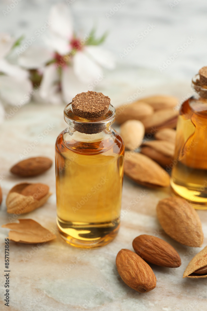 Almond oil in bottle and nuts on color marble table, closeup Almond oil in bottle and nuts on color marble table, closeup