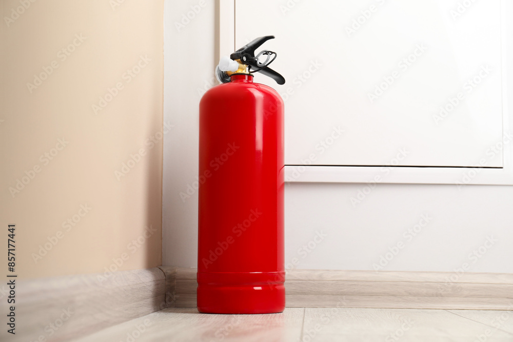 Fire extinguisher on floor near beige wall indoors Fire extinguisher on floor near beige wall indoors