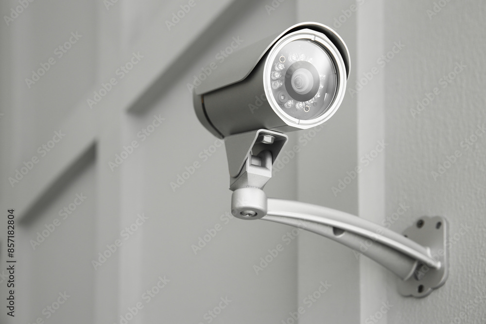 Modern CCTV camera on wall indoors, low angle view Modern CCTV camera on wall indoors, low angle view