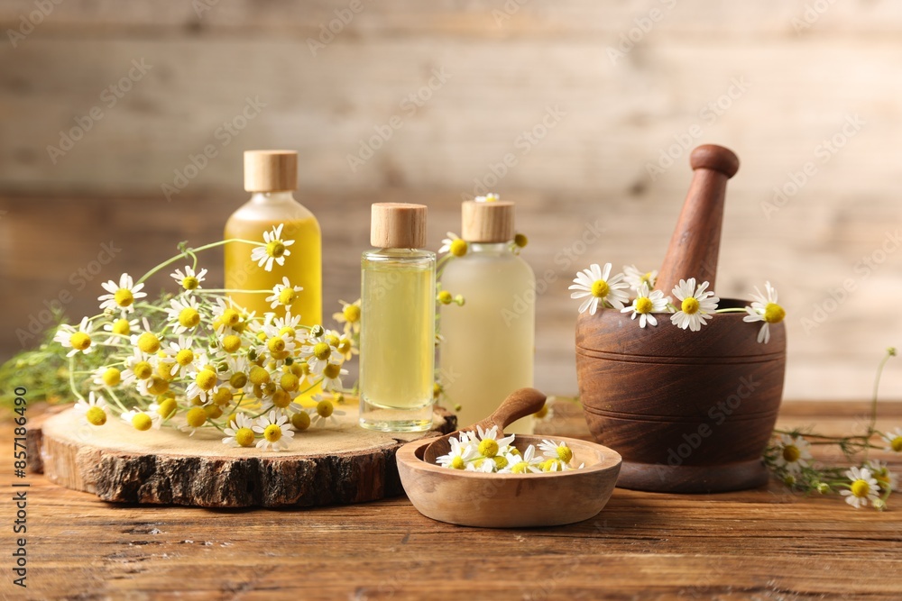 Different flowers and bottles of essential oils on wooden table