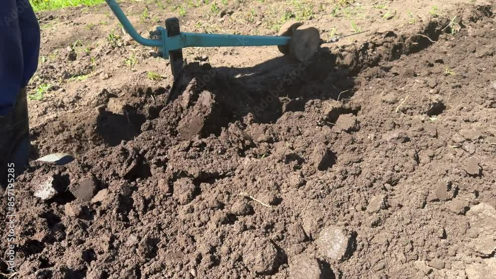 Gardener in spring plow ground soil with electric cultivator Gardener in spring plow ground soil with electric cultivator