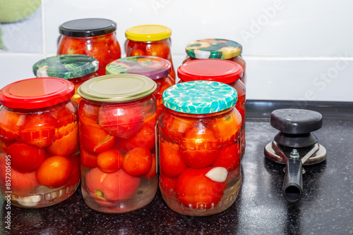 Red ripe tomatoes in glass jars and a mechanical sealer for lids. Preparing vegetables for the winter photo