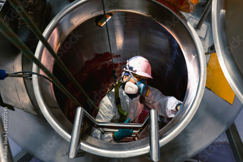 Top view male climbs up the stairs into the tank stainless chemical area inside confined photo