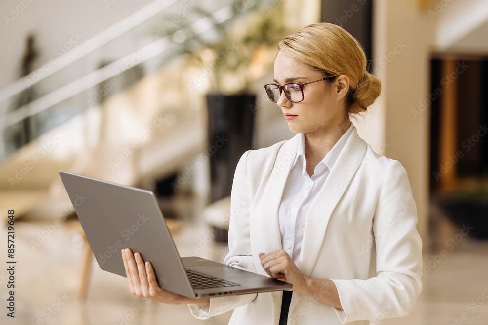 Business, confident woman in a modern business center lounge with a laptop. The concept of a successful business, transaction and modern technology. Business, confident woman in a modern business center lounge with a laptop. The concept of a successful business, transaction and modern technology.
