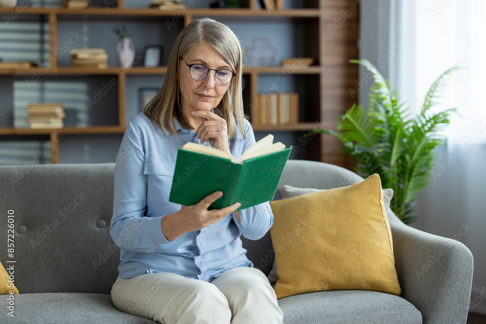 Elderly woman enjoying her reading time while sitting on a comfortable sofa at home. Relaxed and peaceful atmosphere with a book in hand. Elderly woman enjoying her reading time while sitting on a comfortable sofa at home. Relaxed and peaceful atmosphere with a book in hand.