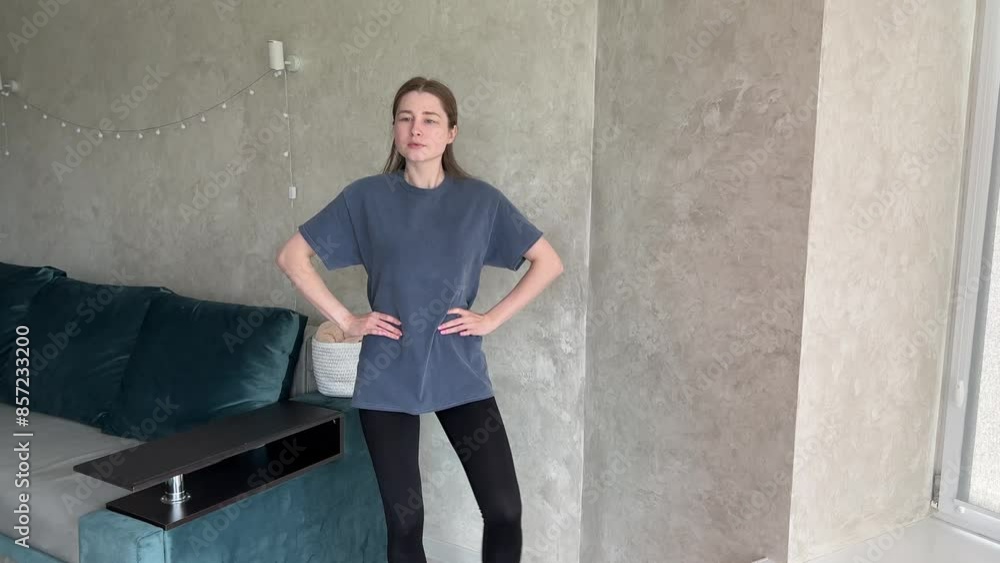 Young woman doing standing stretches in a modern living room, enhancing flexibility and posture. Perfect for fitness and wellness content Young woman doing standing stretches in a modern living room, enhancing flexibility and posture. Perfect for fitness and wellness content