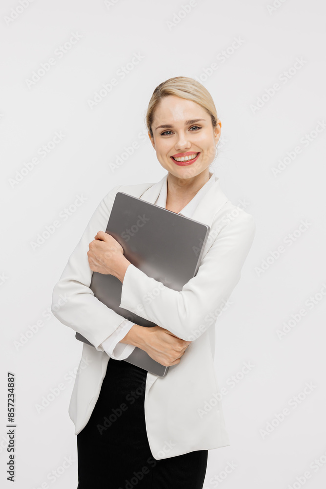Confident blonde woman dressed in stylish business clothes against a white studio background. Business lady uses a laptop. Online work or study concept. Confident blonde woman dressed in stylish business clothes against a white studio background. Business lady uses a laptop. Online work or study concept.