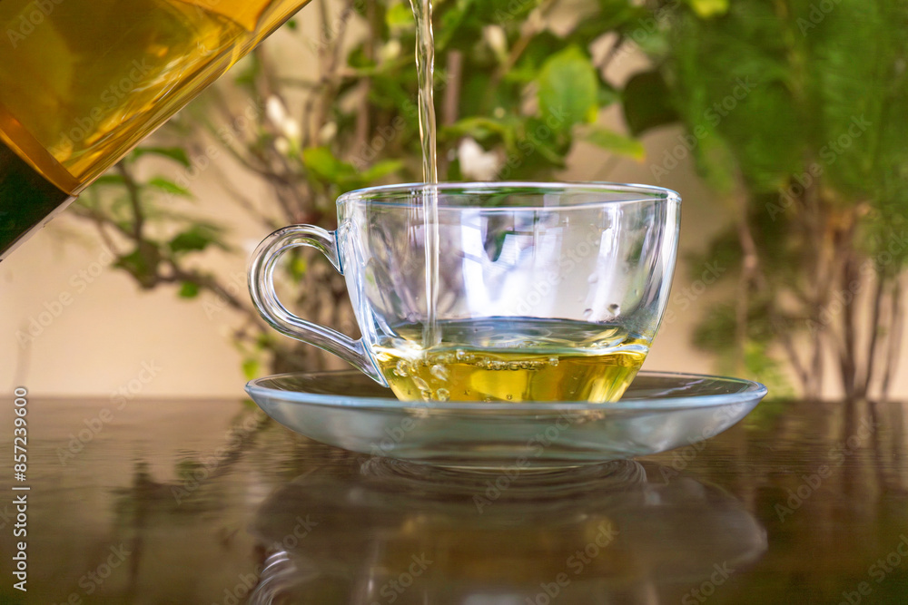 Pouring Organic Green Tea into a transparant glass tea cup in the mountains with green background Pouring Organic Green Tea into a transparant glass tea cup in the mountains with green background