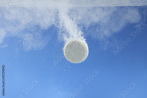 Fotografi Effervescent pill dissolving in water on blue background, closeup