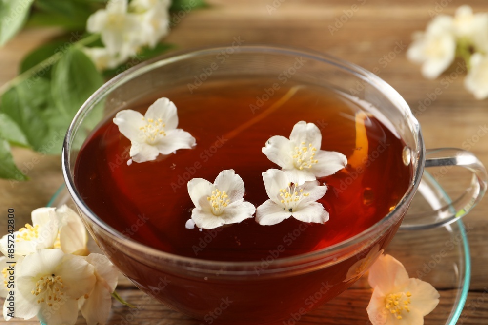 Hot jasmine tea in cup and flowers on wooden table, closeup Hot jasmine tea in cup and flowers on wooden table, closeup