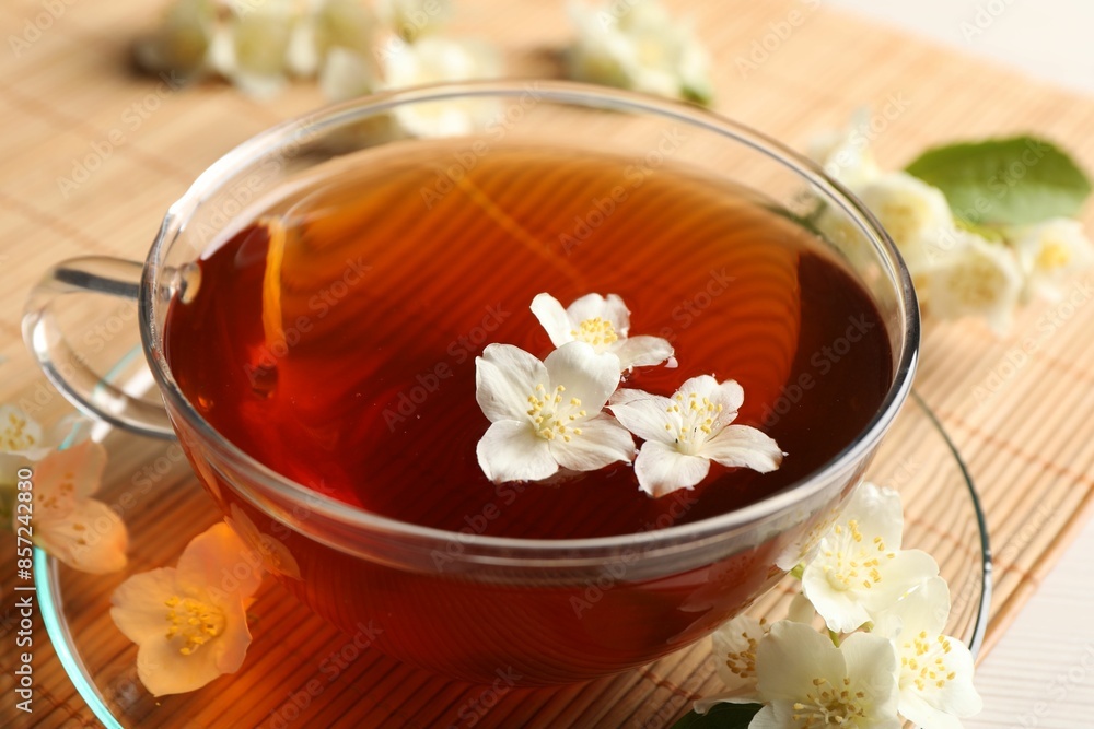 Hot jasmine tea in cup and flowers on white wooden table, closeup Hot jasmine tea in cup and flowers on white wooden table, closeup