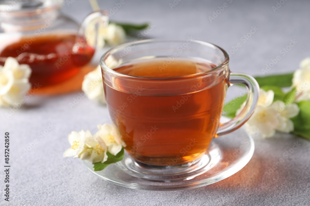 Hot jasmine tea in cup and flowers on light grey table Hot jasmine tea in cup and flowers on light grey table