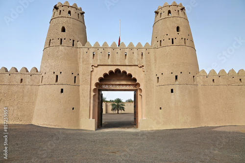 Main gate Al Jahili Fort in Al Ain, Abu Dhabi, with a palm tree visible through the open gate photo