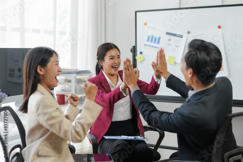 Business team celebrating success with high five in modern office. Diverse colleagues sharing a moment of achievement and joy.