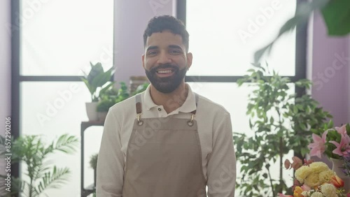 Wallpaper Mural A cheerful hispanic man with a beard wearing an apron stands in a vibrant flower shop full of green plants and colorful blooms. Torontodigital.ca